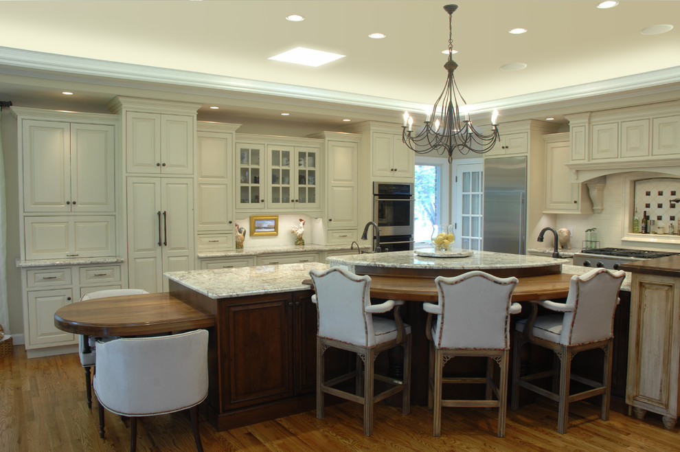Cette photo montre une cuisine chic avec des portes de placard blanches, un plan de travail en granite et un électroménager en acier inoxydable.