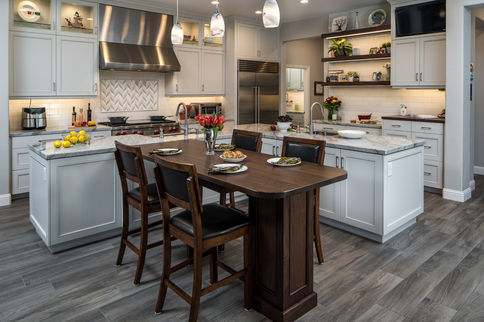 Eat-in kitchen - large transitional l-shaped porcelain tile eat-in kitchen idea in Sacramento with a farmhouse sink, recessed-panel cabinets, white cabinets, quartzite countertops, white backsplash, subway tile backsplash, stainless steel appliances, an island and white countertops
