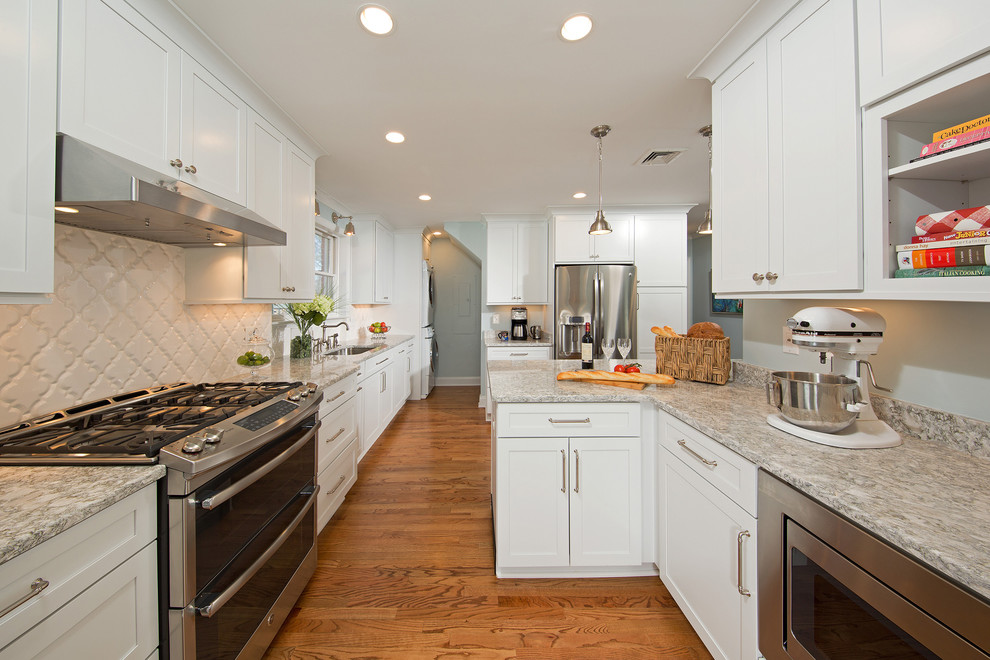 Exempel på ett mellanstort klassiskt kök, med en undermonterad diskho, vita skåp, granitbänkskiva, vitt stänkskydd, stänkskydd i keramik, rostfria vitvaror, mellanmörkt trägolv, en halv köksö och skåp i shakerstil