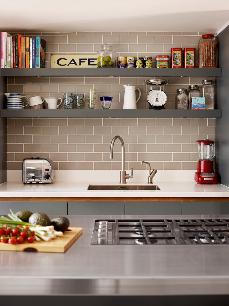 Large trendy kitchen photo in London with an undermount sink, flat-panel cabinets, gray cabinets, stainless steel countertops, gray backsplash, stainless steel appliances, an island and subway tile backsplash
