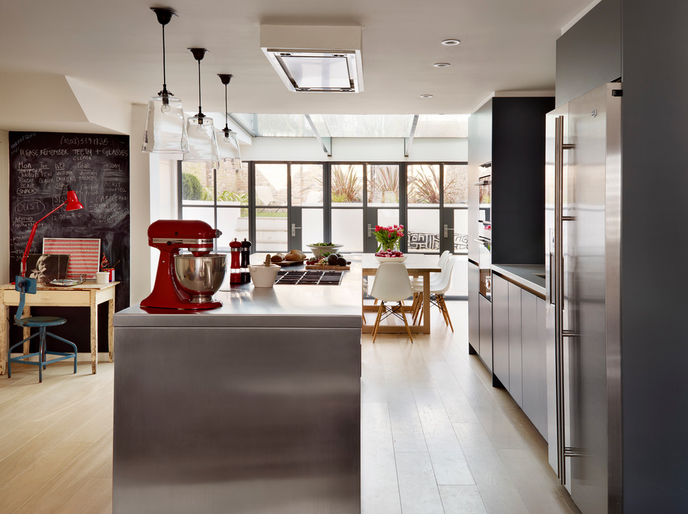 Bild på ett stort funkis kök med öppen planlösning, med en undermonterad diskho, släta luckor, grå skåp, bänkskiva i rostfritt stål, grått stänkskydd, stänkskydd i keramik, rostfria vitvaror, ljust trägolv och en köksö