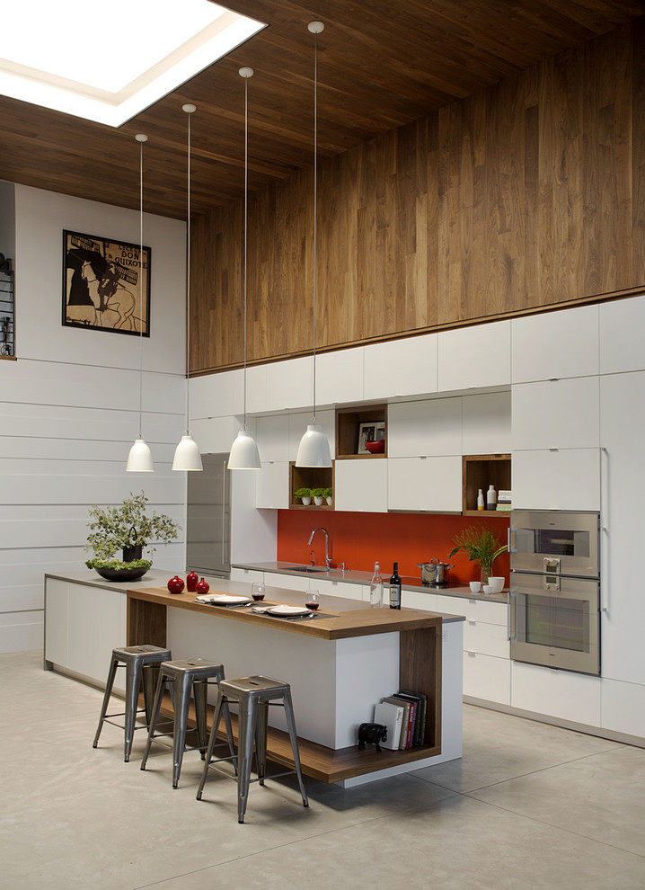 Inspiration for a large contemporary single-wall concrete floor open concept kitchen remodel in Boston with flat-panel cabinets, white cabinets, wood countertops, red backsplash, stainless steel appliances, an island, glass sheet backsplash and an undermount sink