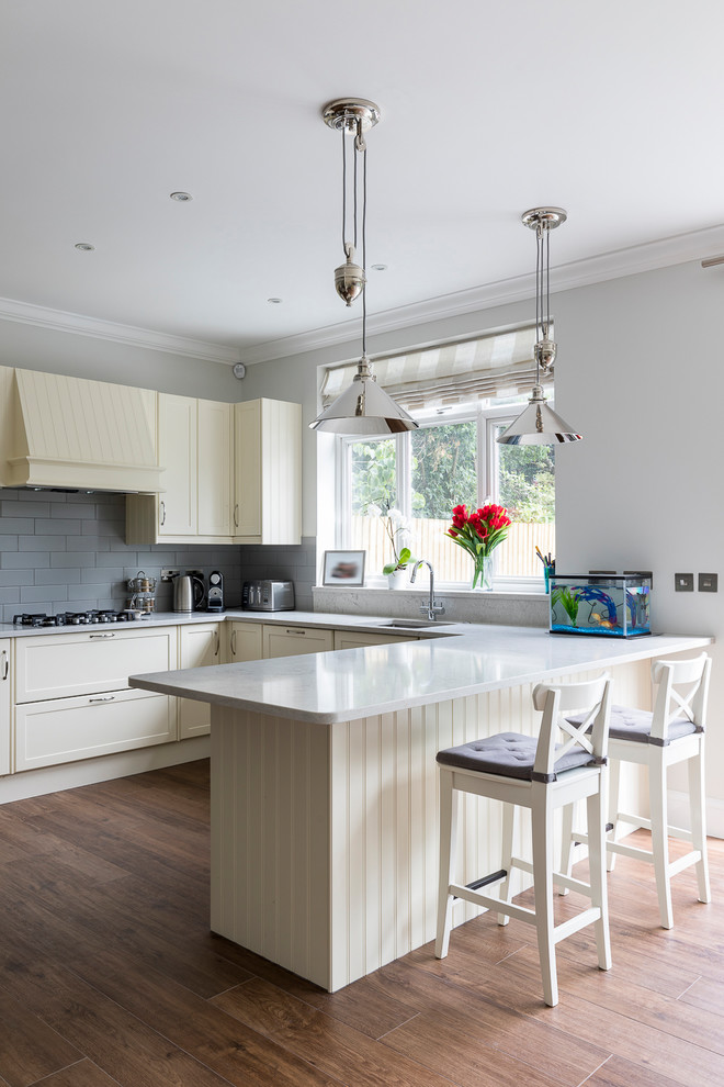 Design ideas for a medium sized classic grey and cream u-shaped open plan kitchen in London with a submerged sink, shaker cabinets, beige cabinets, granite worktops, grey splashback, porcelain splashback, stainless steel appliances, porcelain flooring, a breakfast bar and brown floors.