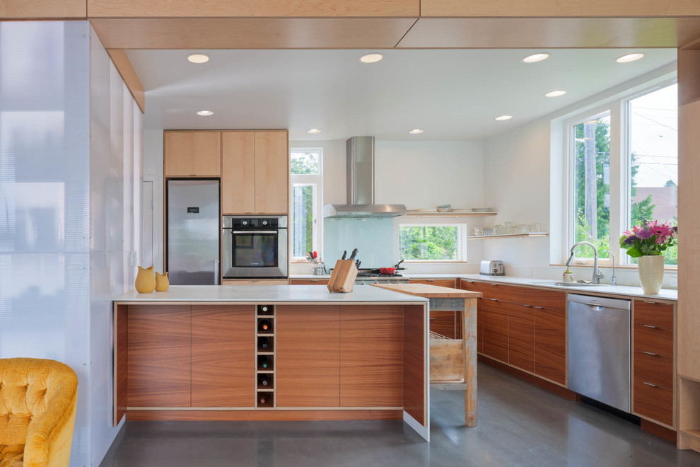 Example of a trendy l-shaped concrete floor kitchen design in Seattle with flat-panel cabinets, medium tone wood cabinets, stainless steel appliances and an island