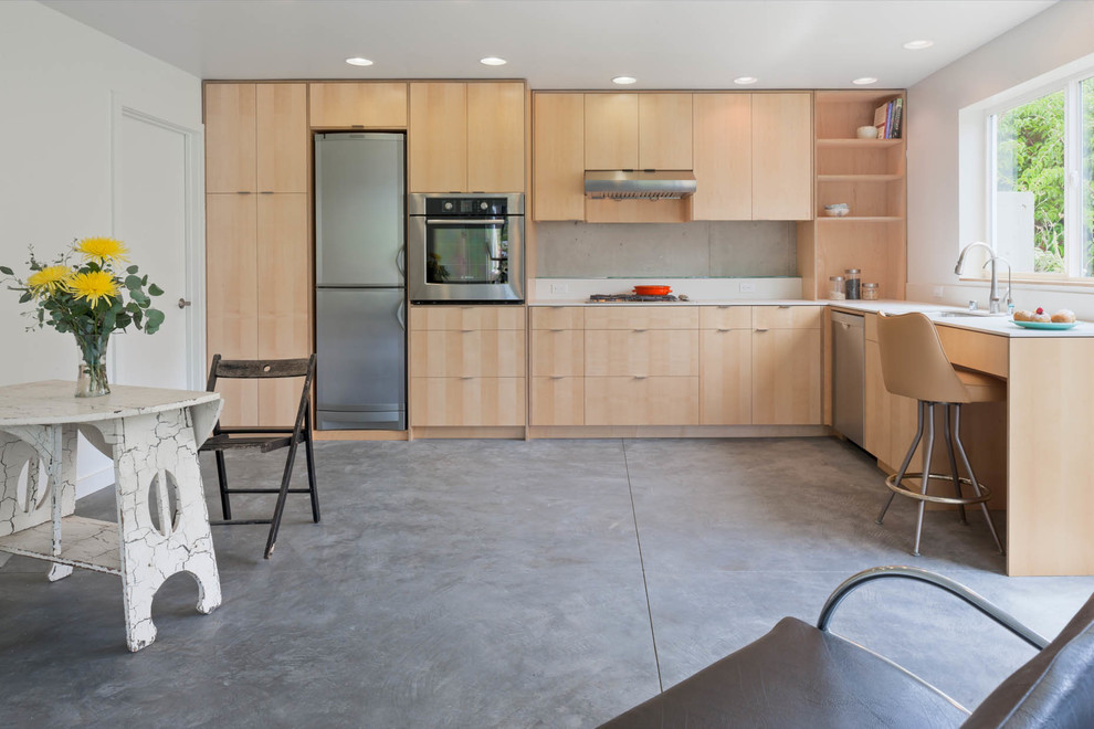 Contemporary l-shaped open plan kitchen in Seattle with flat-panel cabinets, light wood cabinets, stainless steel appliances, concrete flooring and no island.