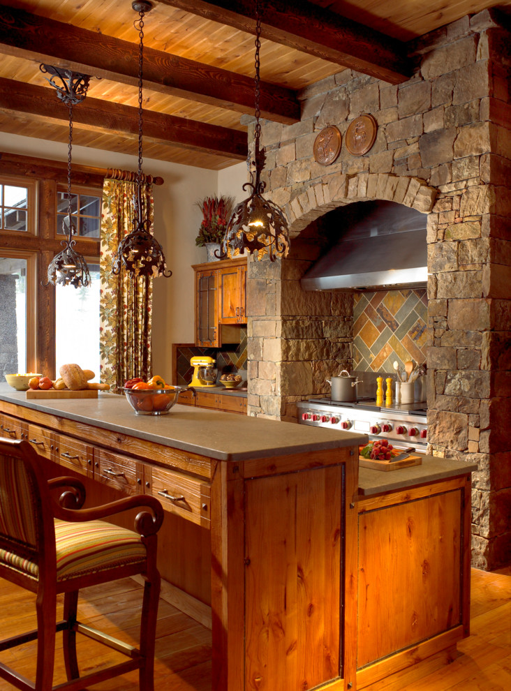 Idée de décoration pour une cuisine chalet en bois brun avec un électroménager en acier inoxydable et une crédence en ardoise.
