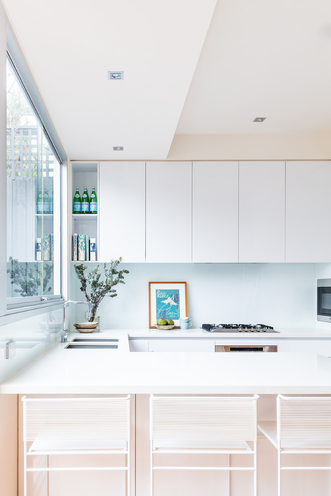 Moderne Küche mit flächenbündigen Schrankfronten, weißen Schränken und Halbinsel in Melbourne
