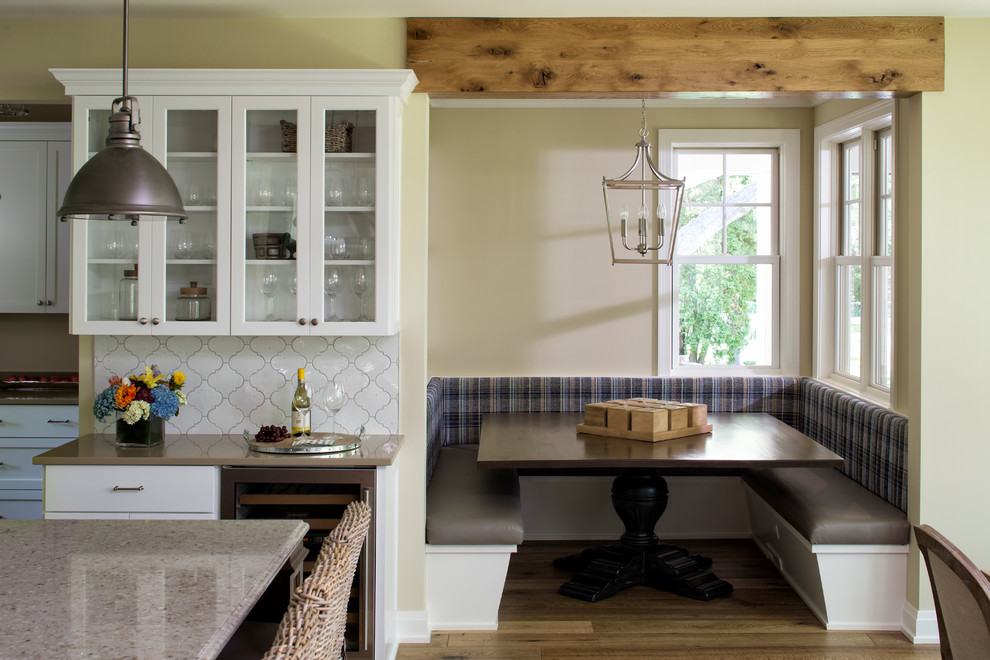 Immagine di una cucina abitabile tradizionale con ante di vetro, ante bianche, paraspruzzi bianco e pavimento in legno massello medio