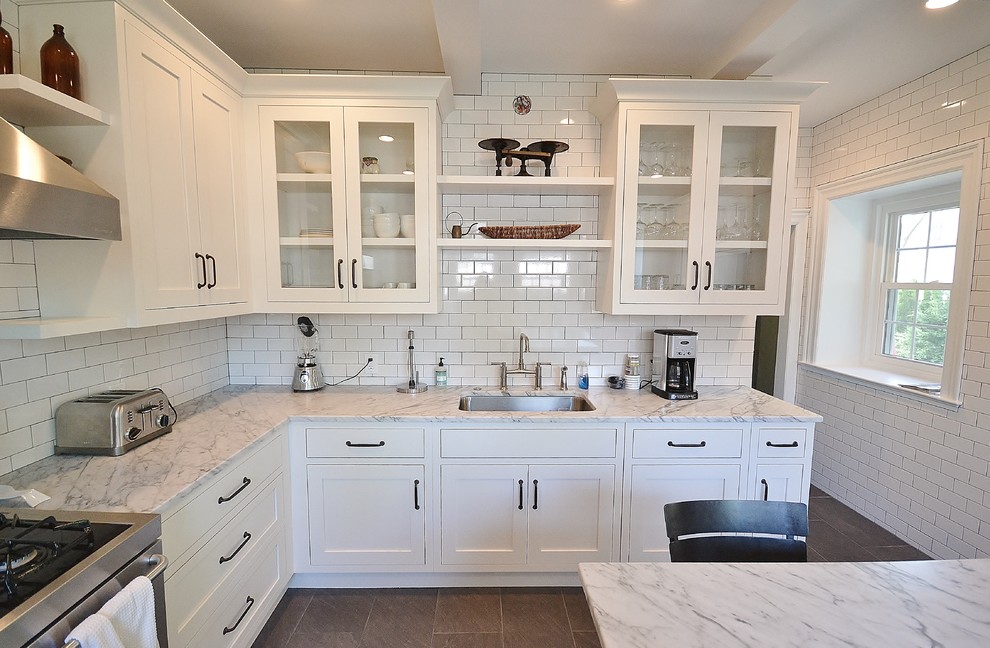 Large traditional u-shaped kitchen/diner in Philadelphia with a submerged sink, white cabinets, marble worktops, white splashback, metro tiled splashback, stainless steel appliances, ceramic flooring, a breakfast bar and glass-front cabinets.