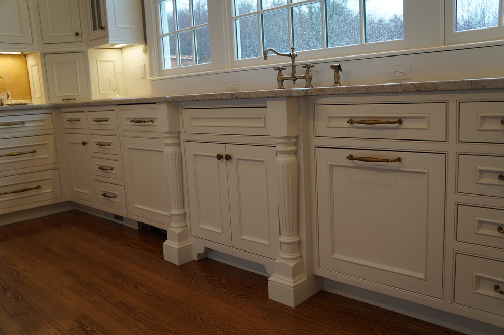 This is an example of a large classic u-shaped kitchen/diner in Boston with a submerged sink, flat-panel cabinets, white cabinets, marble worktops, integrated appliances, light hardwood flooring and an island.