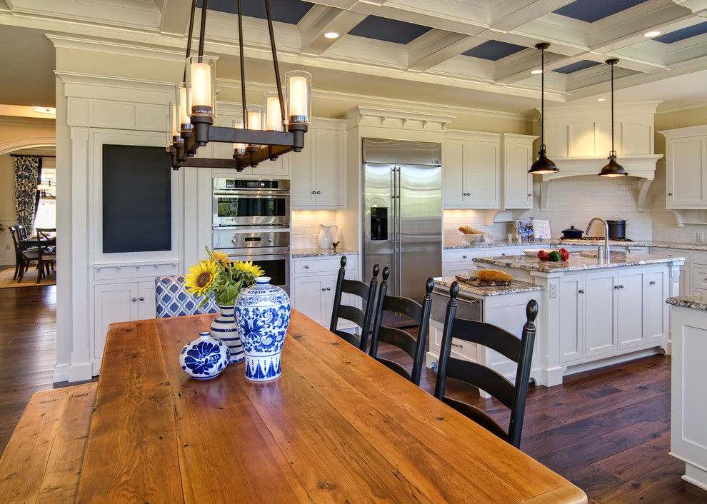 Klassische Küche mit Küchengeräten aus Edelstahl und Rückwand aus Metrofliesen in Sonstige