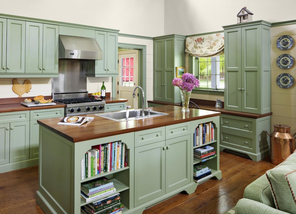 Inspiration for a large timeless l-shaped medium tone wood floor and brown floor open concept kitchen remodel in New York with a drop-in sink, recessed-panel cabinets, green cabinets, wood countertops, an island, white backsplash, wood backsplash, stainless steel appliances and brown countertops