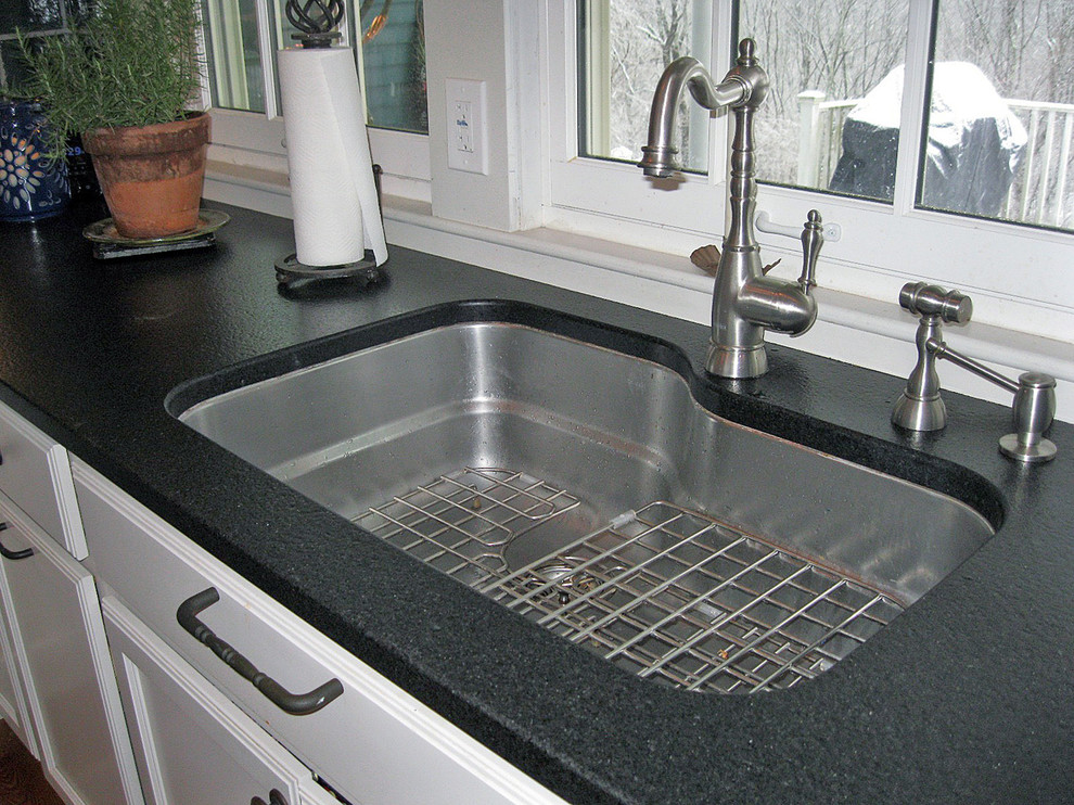 Foto på ett svart kök, med en undermonterad diskho, skåp i shakerstil, vita skåp, granitbänkskiva, blått stänkskydd, stänkskydd i porslinskakel, rostfria vitvaror, mellanmörkt trägolv, en köksö och brunt golv
