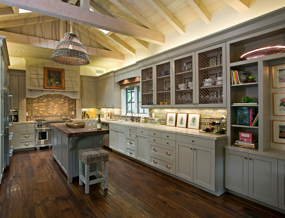 Foto de cocinas en U de estilo de casa de campo con encimera de mármol, puertas de armario grises, electrodomésticos de acero inoxidable, armarios con paneles empotrados, fregadero bajoencimera, salpicadero verde, salpicadero de azulejos tipo metro, suelo de madera en tonos medios, una isla y cortinas