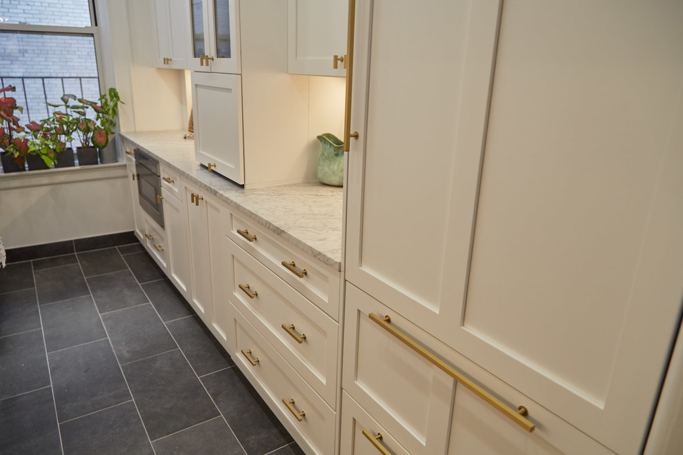 Mid-sized transitional galley cement tile floor and gray floor kitchen photo in New York with a farmhouse sink, shaker cabinets, white cabinets, quartz countertops, white backsplash, ceramic backsplash, stainless steel appliances and gray countertops