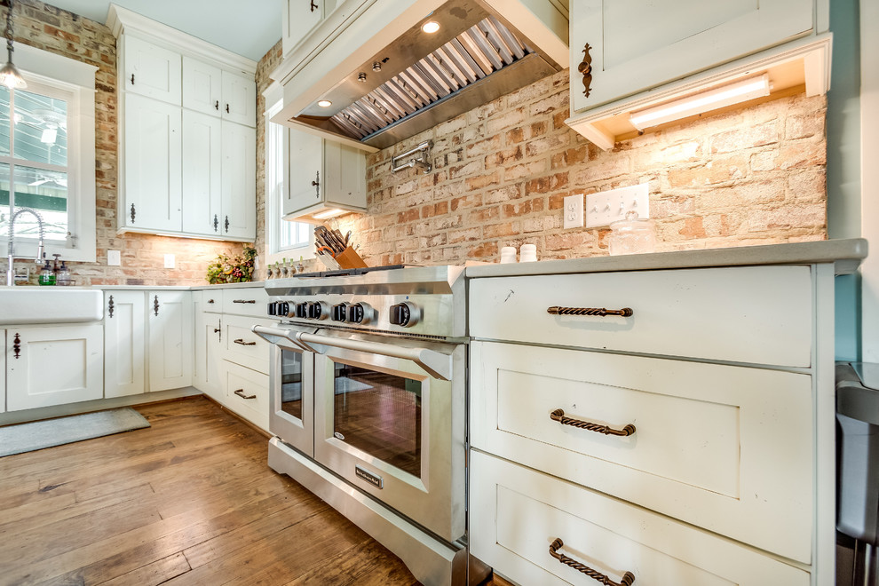 バーミングハムにある高級な広いカントリー風のおしゃれなキッチン (シェーカースタイル扉のキャビネット、白いキャビネット、レンガのキッチンパネル、シルバーの調理設備) の写真