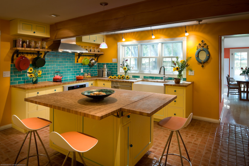 Geschlossene Landhaus Küche in U-Form mit Landhausspüle, gelben Schränken, Arbeitsplatte aus Holz, Rückwand aus Metrofliesen und Küchengeräten aus Edelstahl in Denver