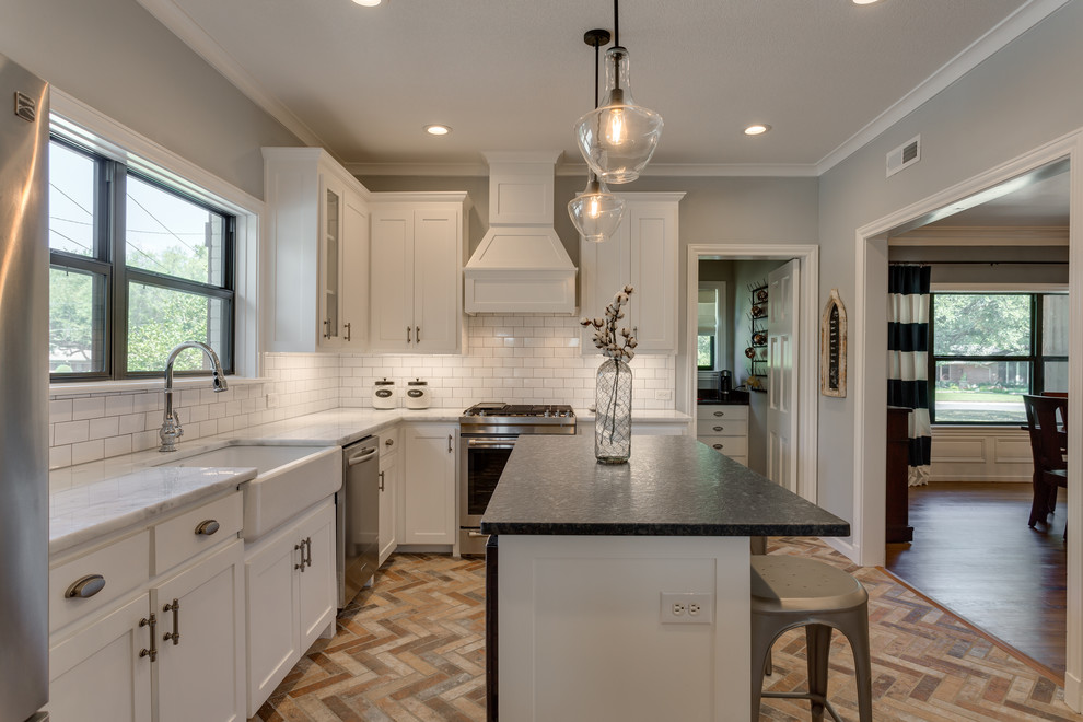 Mid-sized country l-shaped brick floor and multicolored floor eat-in kitchen photo in Dallas with a farmhouse sink, shaker cabinets, white cabinets, marble countertops, white backsplash, subway tile backsplash, stainless steel appliances, an island and multicolored countertops