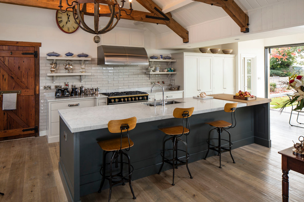 Inspiration for a large rural u-shaped kitchen/diner in Dublin with an island, a submerged sink, recessed-panel cabinets, blue cabinets, white splashback and light hardwood flooring.