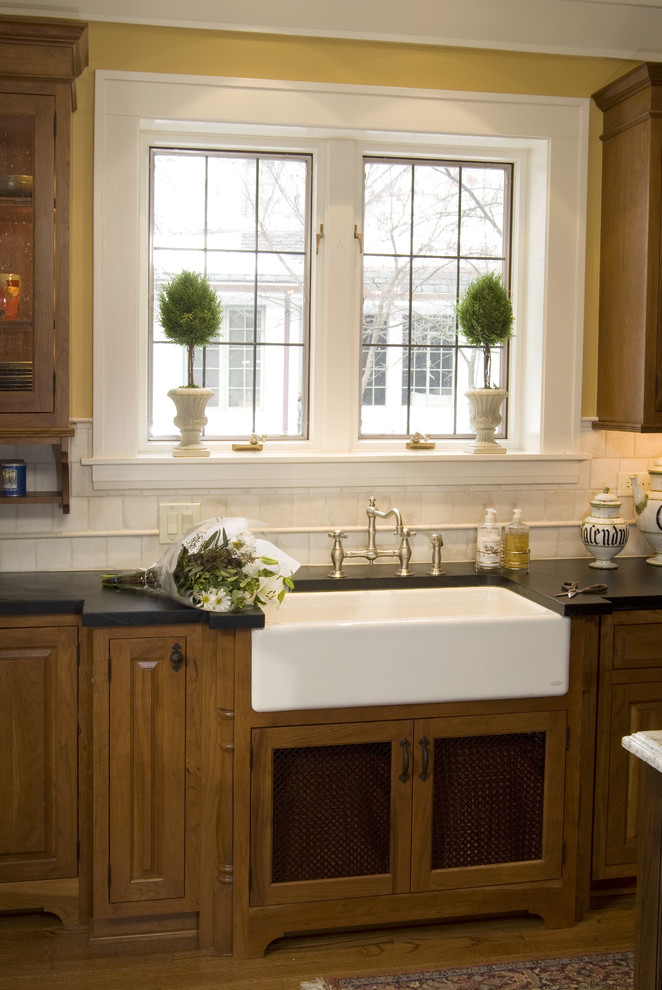 Example of a classic kitchen design in Chicago with a farmhouse sink, medium tone wood cabinets and soapstone countertops