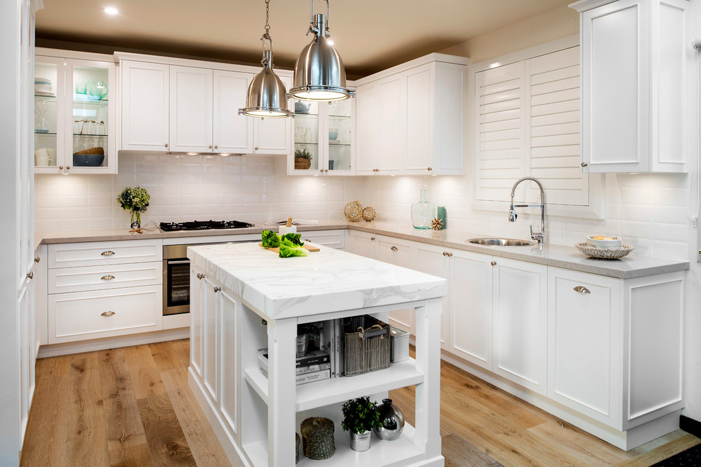 Inspiration for a coastal u-shaped light wood floor kitchen remodel in Gold Coast - Tweed with a single-bowl sink, recessed-panel cabinets, white cabinets, white backsplash, stainless steel appliances and an island