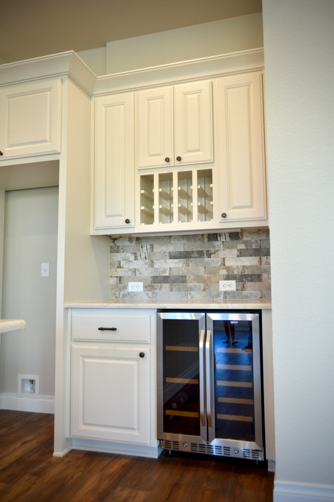 Bild på ett stort lantligt vit vitt kök, med en rustik diskho, luckor med upphöjd panel, vita skåp, bänkskiva i kvarts, flerfärgad stänkskydd, stänkskydd i travertin, rostfria vitvaror, vinylgolv, en köksö och flerfärgat golv