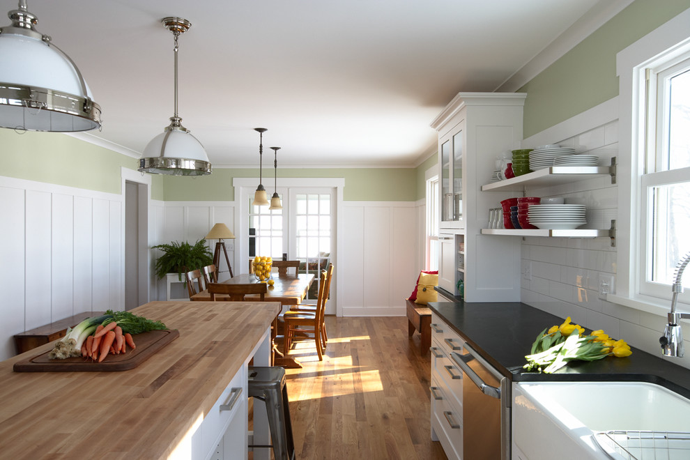 Inspiration for a large timeless l-shaped medium tone wood floor eat-in kitchen remodel in Minneapolis with white cabinets, white backsplash, an island, a farmhouse sink, shaker cabinets, granite countertops, subway tile backsplash and stainless steel appliances