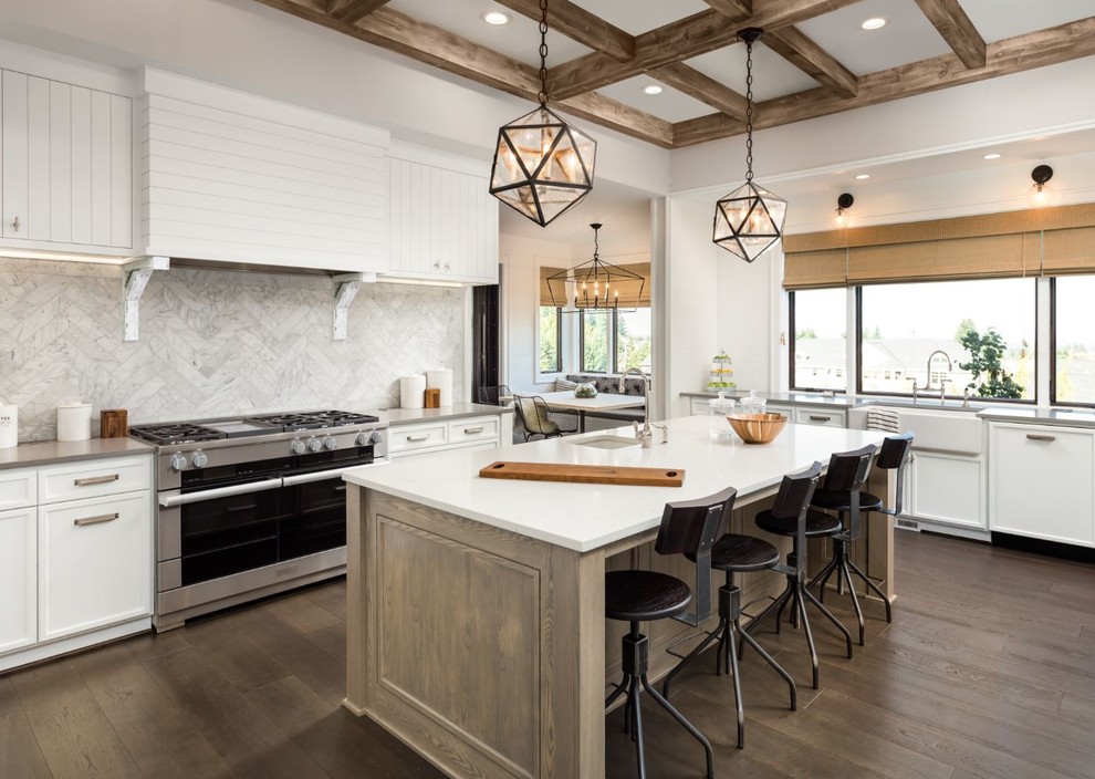 Foto på ett lantligt grå kök, med en undermonterad diskho, luckor med infälld panel, vita skåp, flerfärgad stänkskydd, rostfria vitvaror, mörkt trägolv, en köksö och brunt golv