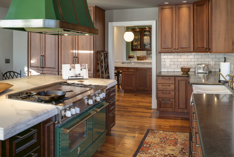 Huge country l-shaped medium tone wood floor open concept kitchen photo in Other with a farmhouse sink, raised-panel cabinets, medium tone wood cabinets, marble countertops, white backsplash, stone tile backsplash, colored appliances and an island