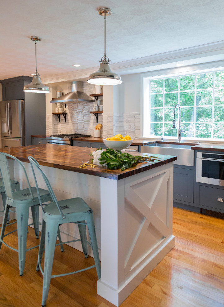 ボストンにあるお手頃価格の中くらいなカントリー風のおしゃれなキッチン (エプロンフロントシンク、インセット扉のキャビネット、白いキャビネット、木材カウンター、白いキッチンパネル、サブウェイタイルのキッチンパネル、シルバーの調理設備、無垢フローリング、茶色い床、茶色いキッチンカウンター) の写真