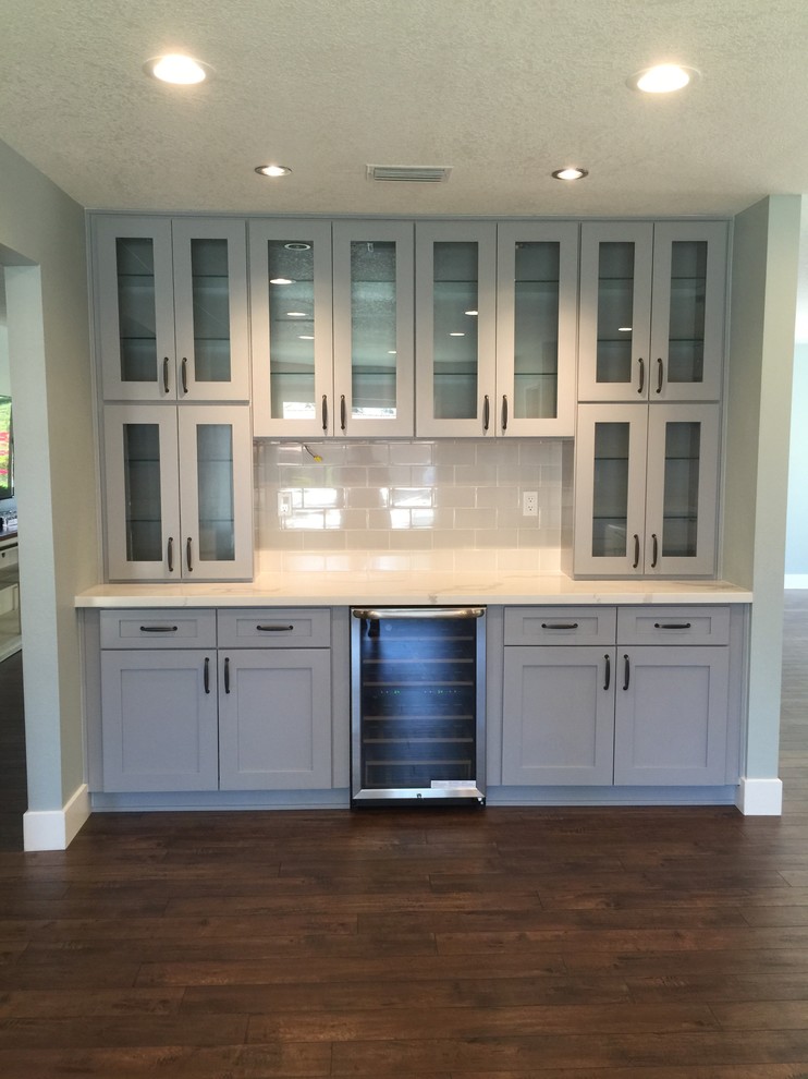 This is an example of a large rural u-shaped open plan kitchen in Los Angeles with a belfast sink, shaker cabinets, white cabinets, quartz worktops, grey splashback, metro tiled splashback, stainless steel appliances and an island.