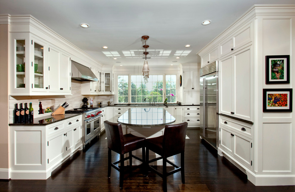 Exempel på ett mellanstort klassiskt u-kök, med en undermonterad diskho, släta luckor, vita skåp, rostfria vitvaror, mörkt trägolv och en köksö