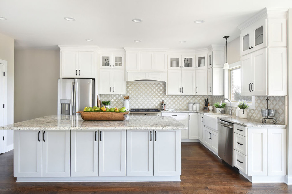 Traditional l-shaped kitchen in Atlanta with a belfast sink, shaker cabinets, white cabinets, multi-coloured splashback, stainless steel appliances, dark hardwood flooring, an island, brown floors and grey worktops.