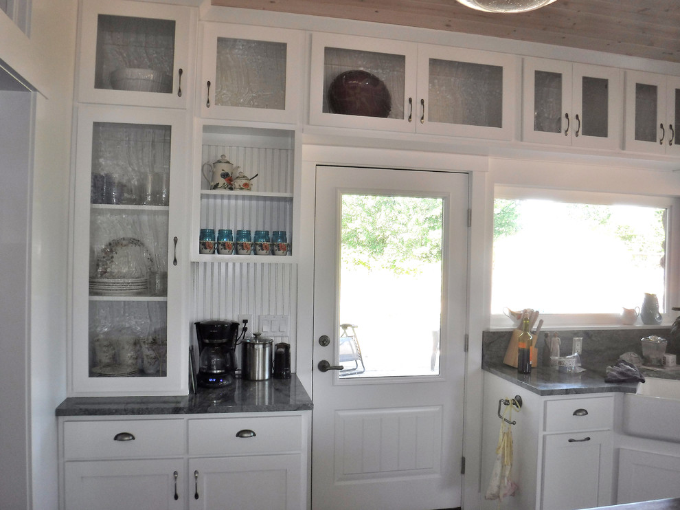 Bild på ett mellanstort, avskilt lantligt u-kök, med en rustik diskho, skåp i shakerstil, vita skåp, granitbänkskiva, rostfria vitvaror, en köksö, grönt stänkskydd och klinkergolv i porslin