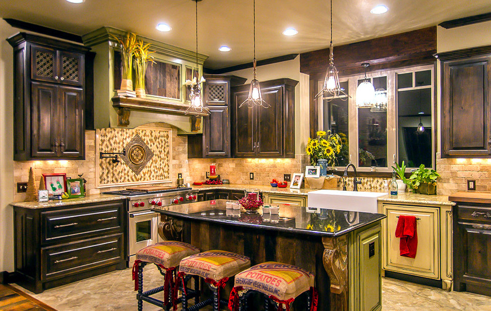 Lantlig inredning av ett kök och matrum, med en rustik diskho, luckor med upphöjd panel, skåp i mörkt trä, granitbänkskiva, beige stänkskydd, stänkskydd i stenkakel, rostfria vitvaror, travertin golv och en köksö