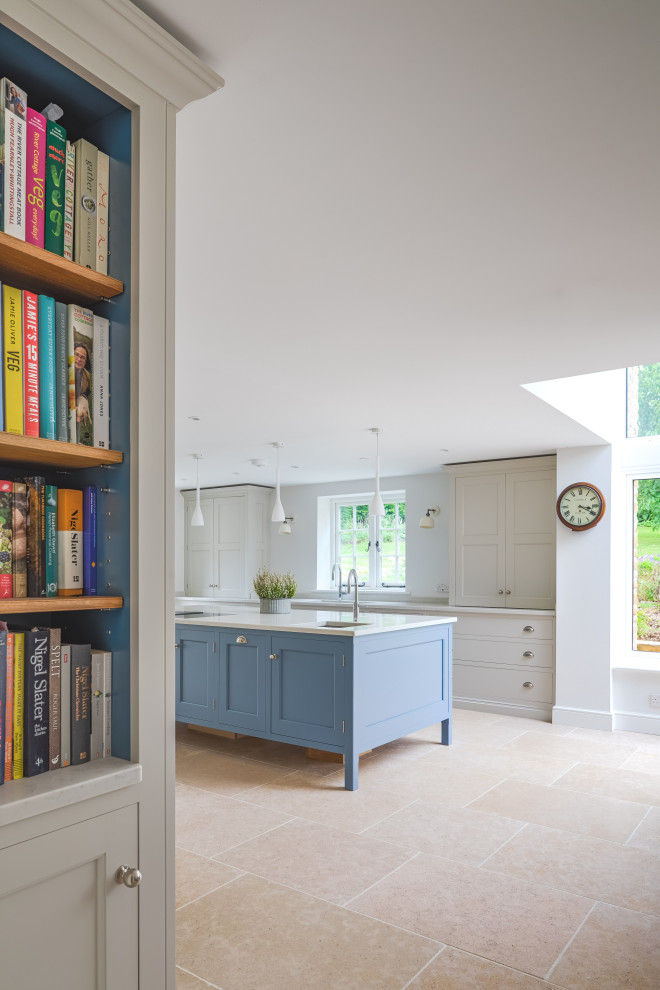 This is an example of a classic kitchen in Dorset with recessed-panel cabinets, limestone flooring, an island and white worktops.