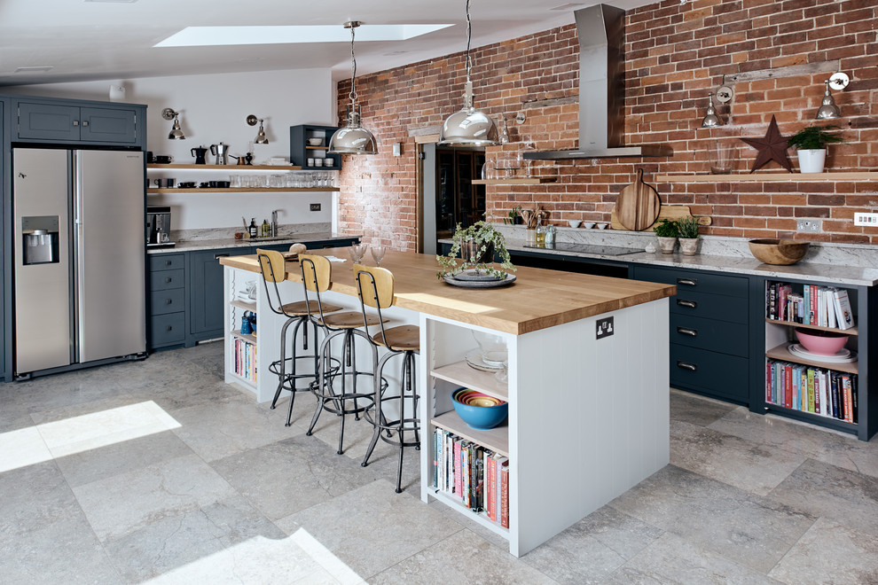 Foto på ett mellanstort industriellt kök, med en undermonterad diskho, luckor med infälld panel, blå skåp, marmorbänkskiva, marmorgolv, en köksö, grått golv och rostfria vitvaror