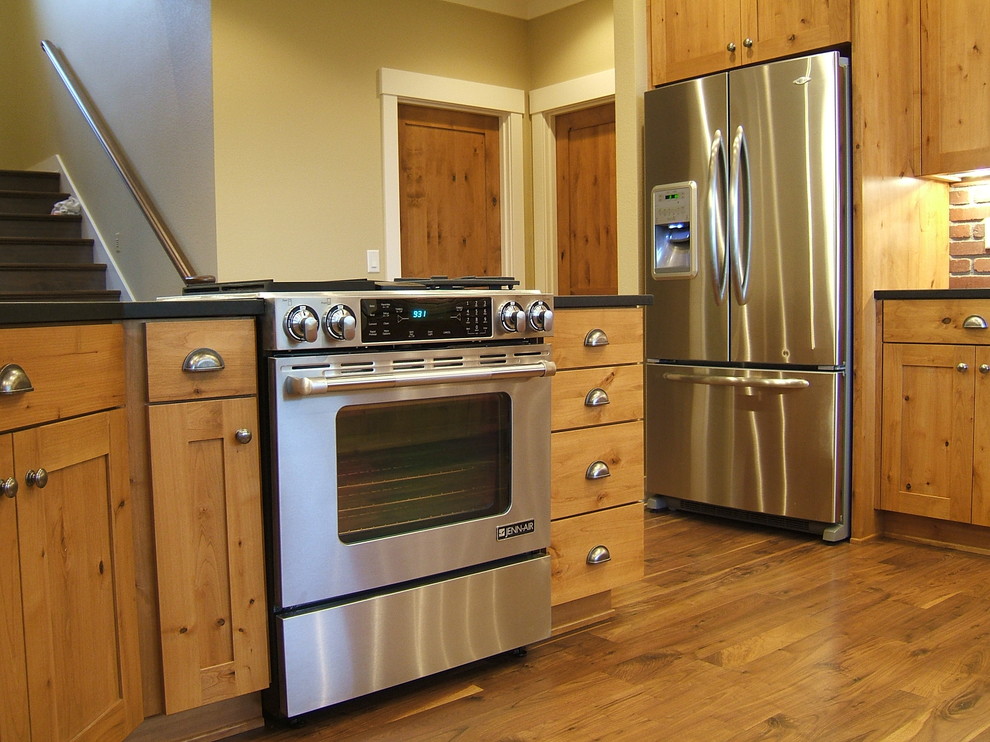 Ejemplo de cocinas en L de estilo de casa de campo abierta con armarios con paneles empotrados, puertas de armario de madera oscura, encimera de granito y electrodomésticos de acero inoxidable