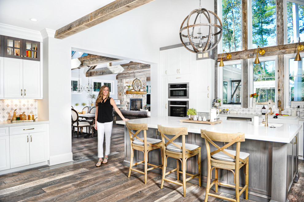 Mid-sized farmhouse l-shaped medium tone wood floor, brown floor and vaulted ceiling eat-in kitchen photo in Raleigh with a farmhouse sink, shaker cabinets, white cabinets, quartz countertops, white backsplash, ceramic backsplash, paneled appliances, an island and white countertops