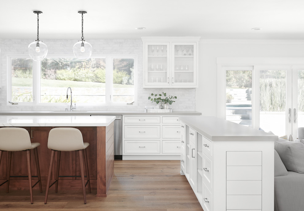 Medium sized traditional u-shaped open plan kitchen in San Francisco with a submerged sink, shaker cabinets, white cabinets, marble worktops, grey splashback, marble splashback, stainless steel appliances, medium hardwood flooring, multiple islands, brown floors and white worktops.