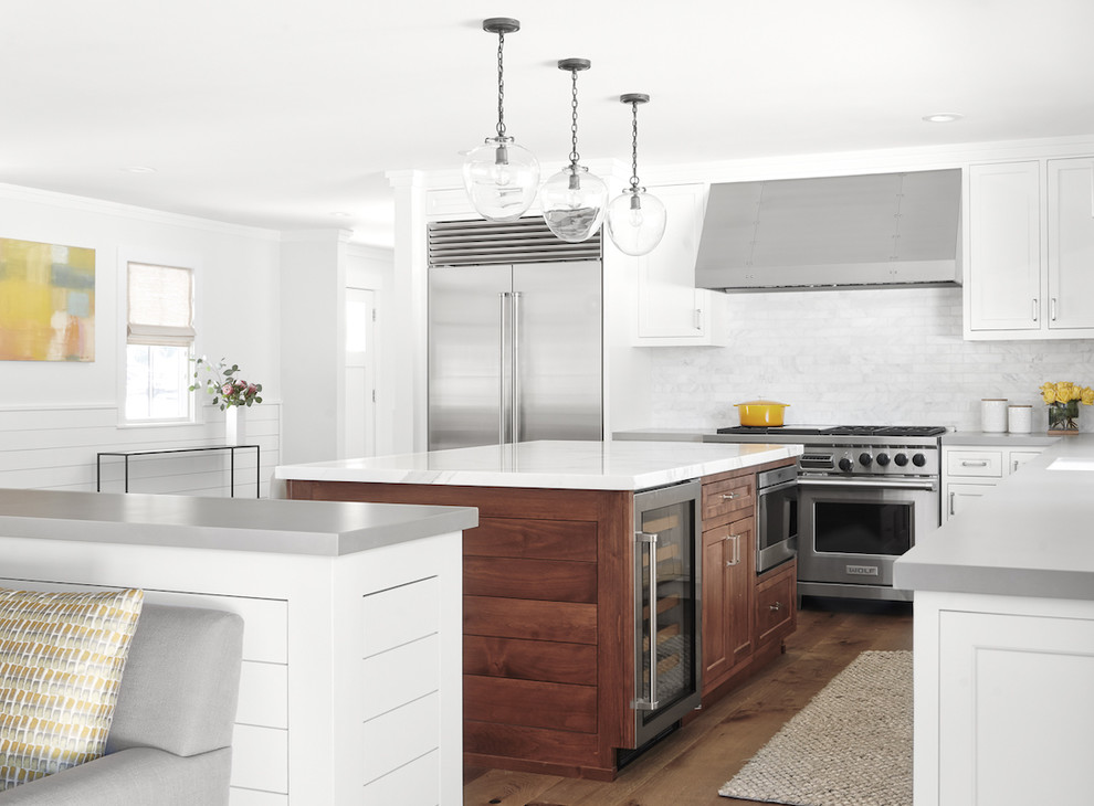 Photo of a medium sized classic l-shaped open plan kitchen in San Francisco with a submerged sink, shaker cabinets, white cabinets, marble worktops, white splashback, marble splashback, stainless steel appliances, medium hardwood flooring, multiple islands, brown floors and white worktops.