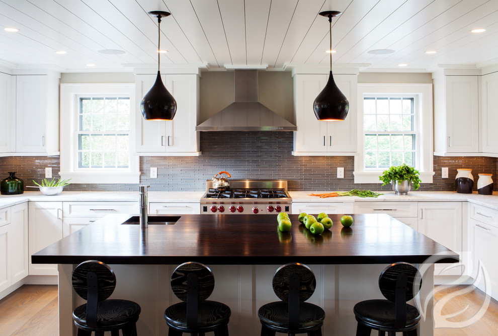 Inspiration for a large farmhouse u-shaped open plan kitchen in Chicago with a submerged sink, recessed-panel cabinets, white cabinets, engineered stone countertops, grey splashback, glass tiled splashback, stainless steel appliances, dark hardwood flooring and an island.