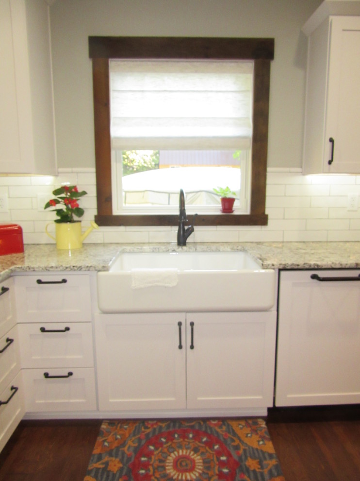 Exempel på ett lantligt kök, med en rustik diskho, skåp i shakerstil, vita skåp, granitbänkskiva, vitt stänkskydd, stänkskydd i porslinskakel, vita vitvaror, mörkt trägolv och en köksö