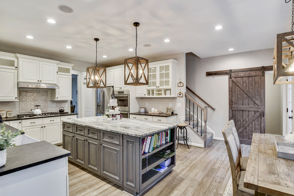 Mid-sized cottage u-shaped bamboo floor and gray floor eat-in kitchen photo in DC Metro with a farmhouse sink, raised-panel cabinets, beige cabinets, granite countertops, white backsplash, ceramic backsplash, stainless steel appliances, an island and gray countertops