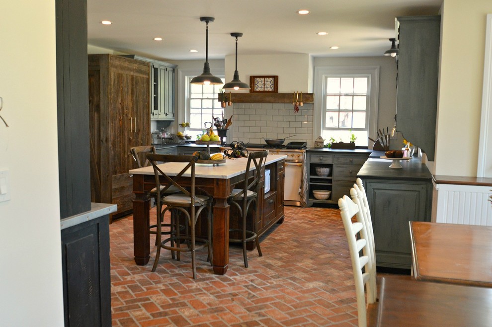 Inredning av ett lantligt avskilt, stort l-kök, med en rustik diskho, luckor med upphöjd panel, grå skåp, marmorbänkskiva, grått stänkskydd, stänkskydd i tunnelbanekakel, vita vitvaror, tegelgolv, en köksö och rött golv