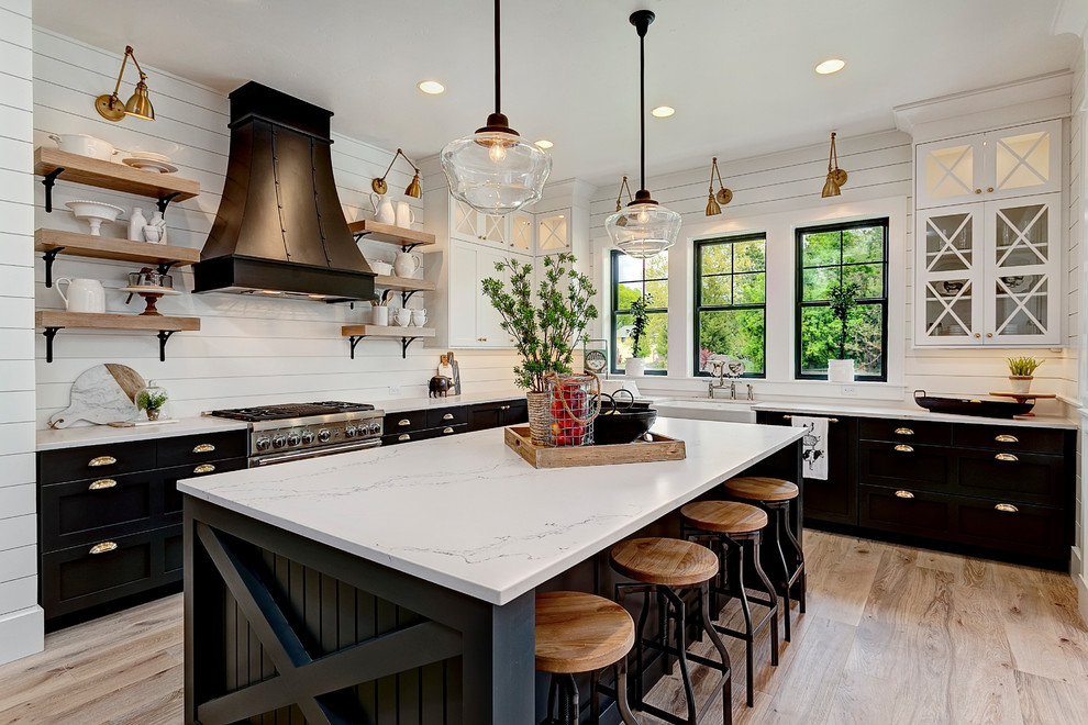Example of a farmhouse l-shaped medium tone wood floor and brown floor kitchen design in Los Angeles with quartz countertops, a farmhouse sink, shaker cabinets, stainless steel appliances and an island