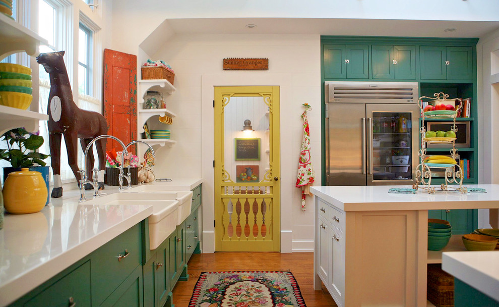 Geschlossene Landhausstil Küche in U-Form mit Landhausspüle, Schrankfronten im Shaker-Stil, grünen Schränken, Küchengeräten aus Edelstahl, braunem Holzboden und Kücheninsel in Los Angeles
