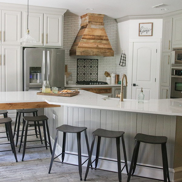 This is an example of a farmhouse kitchen/diner in Dallas with a belfast sink, quartz worktops, metro tiled splashback, stainless steel appliances and an island.