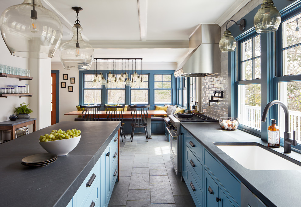 Lantlig inredning av ett mellanstort kök och matrum, med en enkel diskho, blå skåp, bänkskiva i kalksten, vitt stänkskydd, stänkskydd i tunnelbanekakel, rostfria vitvaror, skiffergolv, en köksö och grått golv