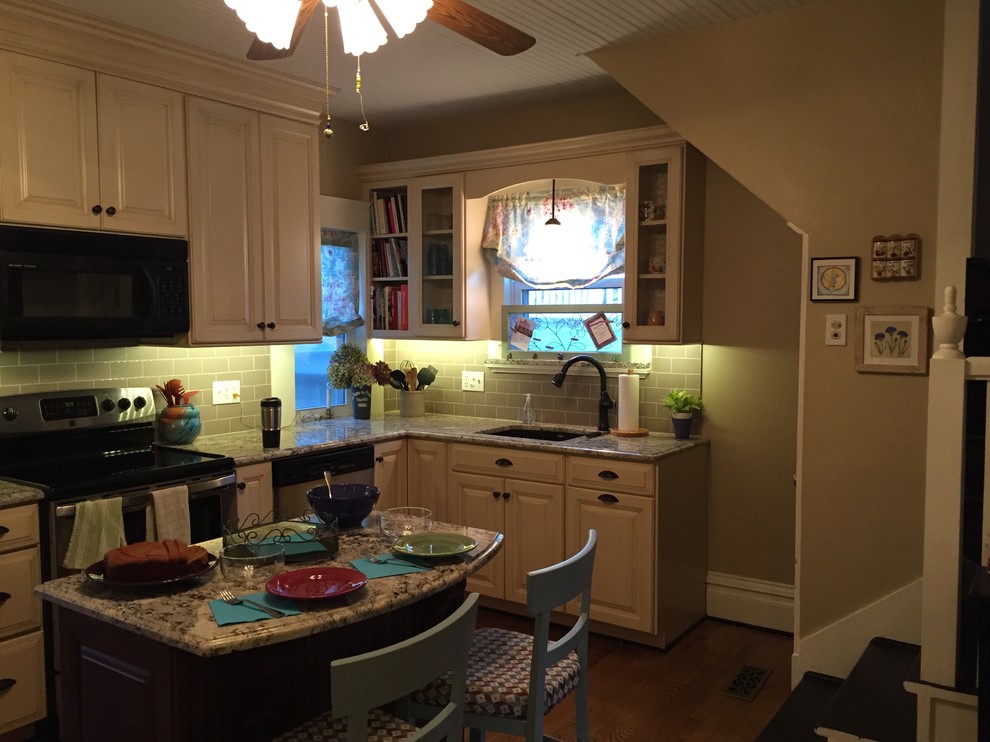 Foto på ett litet lantligt linjärt kök och matrum, med en enkel diskho, luckor med upphöjd panel, skåp i slitet trä, granitbänkskiva, grönt stänkskydd, stänkskydd i keramik, svarta vitvaror, mörkt trägolv och en köksö
